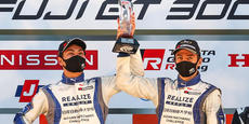 Drivers Kiyoto Fujinami (left) and Joao Paulo de Oliveira on the podium with their championship trophy